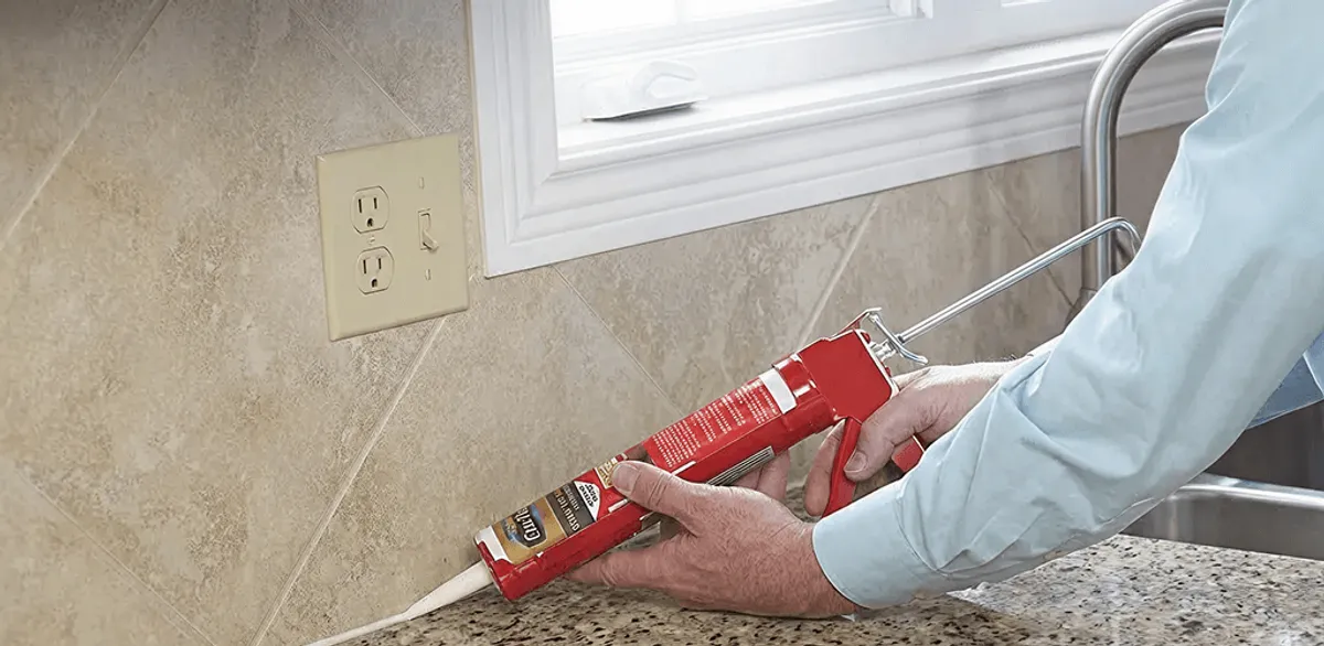 Handyman applying caulk along a kitchen backsplash and countertop seam in Sacramento, CA