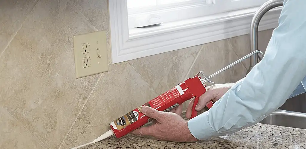 Handyman applying caulk along a kitchen backsplash and countertop seam in Sacramento, CA