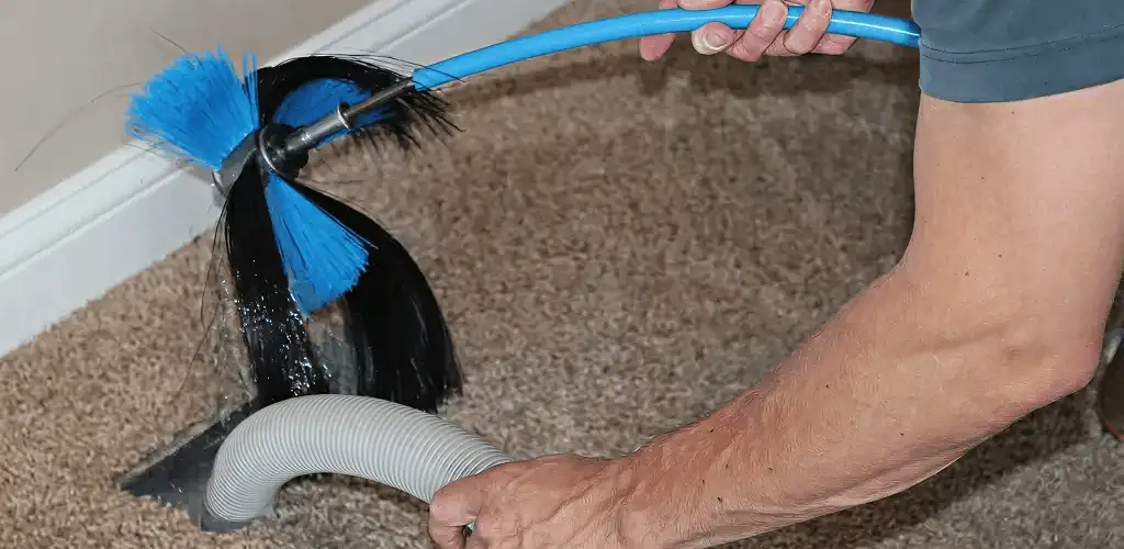 Dryer vent cleaning technician brushing lint from a vent line in Sacramento, CA