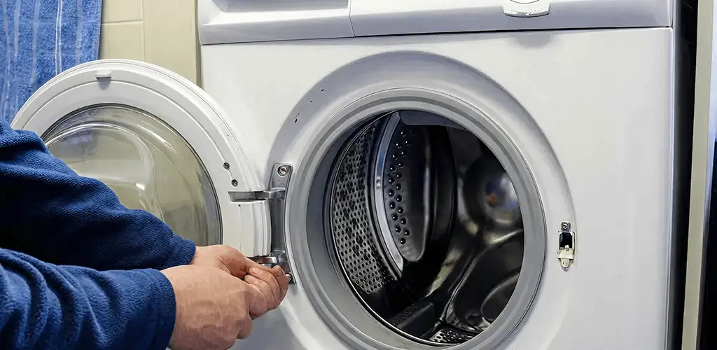 Washing machine repair handyman checking a front-load washer door and latch in Sacramento, CA