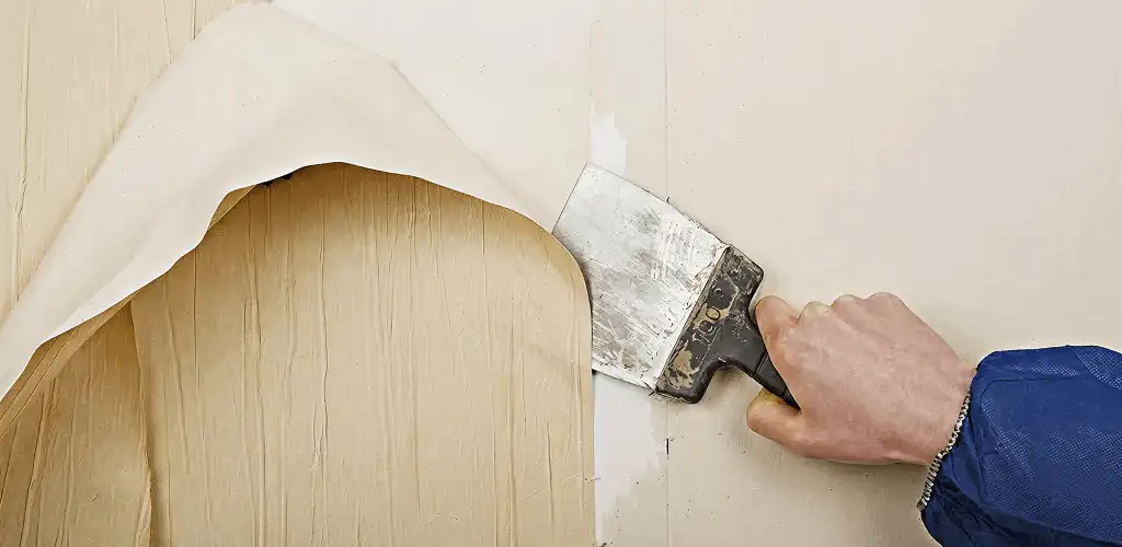 Handyman removing wallpaper with a scraper for wall preparation in Sacramento, CA