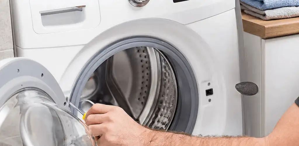 Handyman repairing a front-load washing machine and inspecting the drum in Sacramento, CA