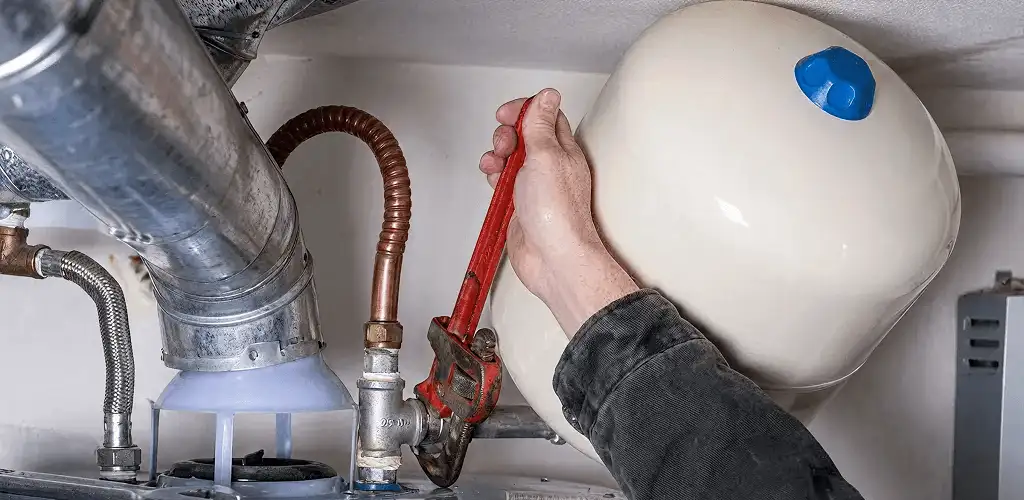 Water heater repair technician tightening plumbing connections near a tank unit in Sacramento, CA