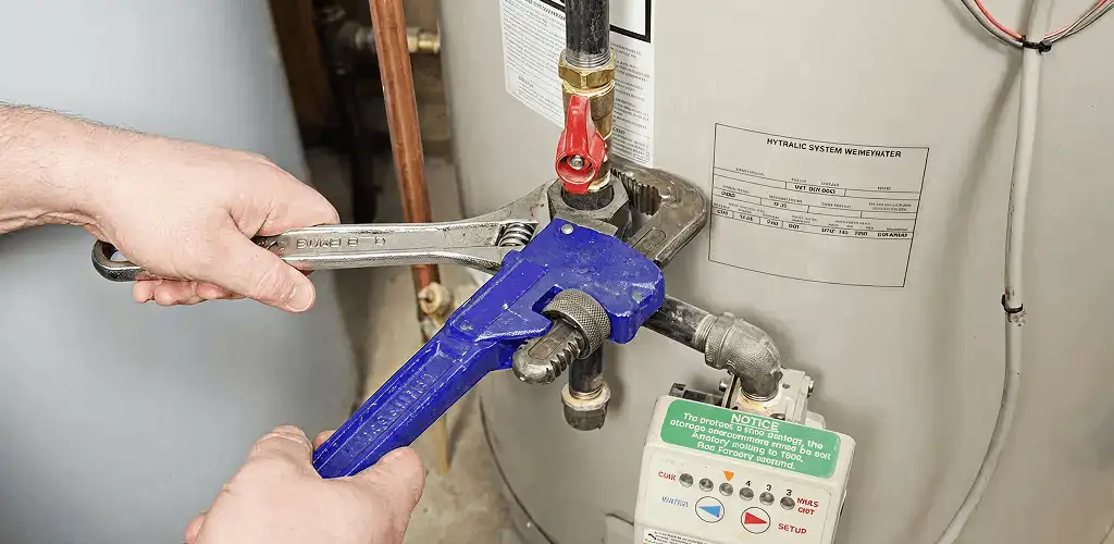 Water heater repair technician tightening the shutoff valve and supply line in Sacramento, CA